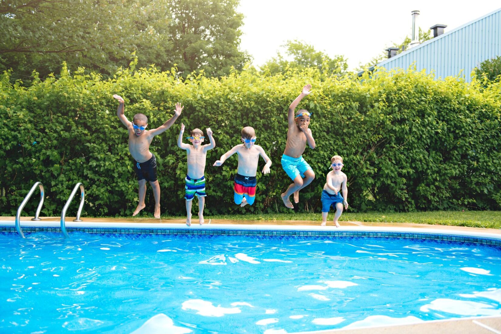 Five kids jumping into the pool.