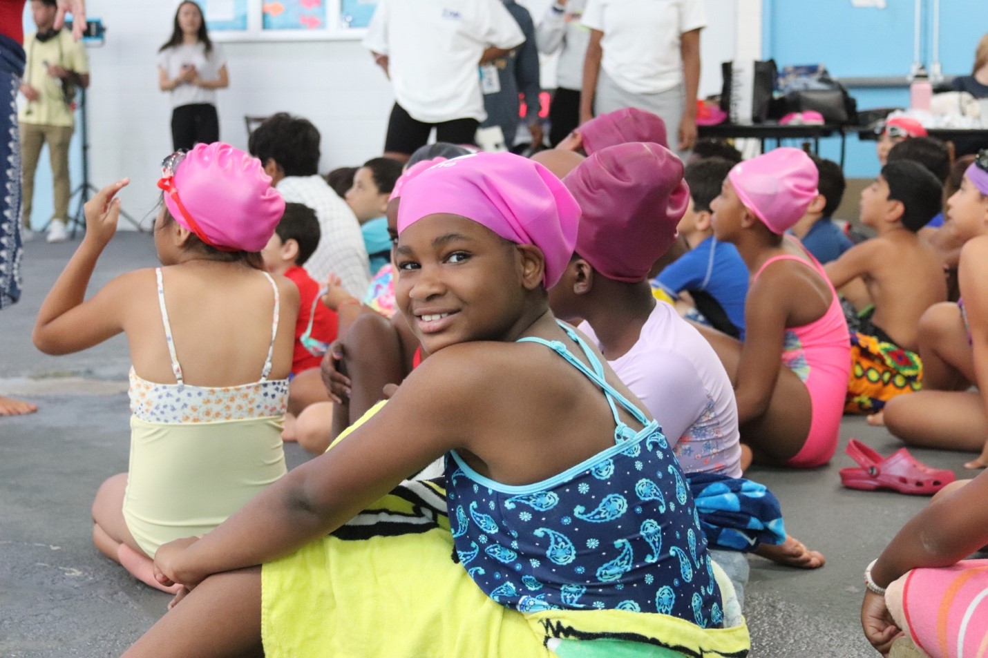 Girl smiles at the camera while sitting in swim apparel